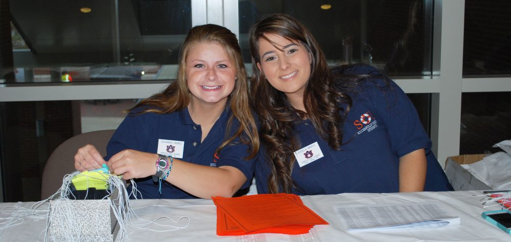 Two female students smiling at check in